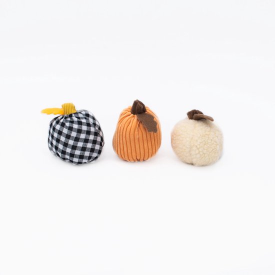Drie stoffen pompoenen op een witte achtergrond: zwart-wit geruite, oranje ribbel, en crème met textuur.