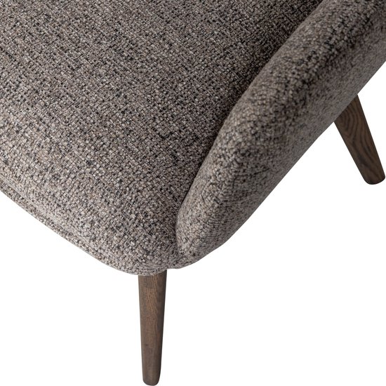 Zicht op de armleuning van een taupe stoffen stoel met houten poten.