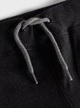 Detail van de tailleband van een zwarte joggingbroek met grijze veter