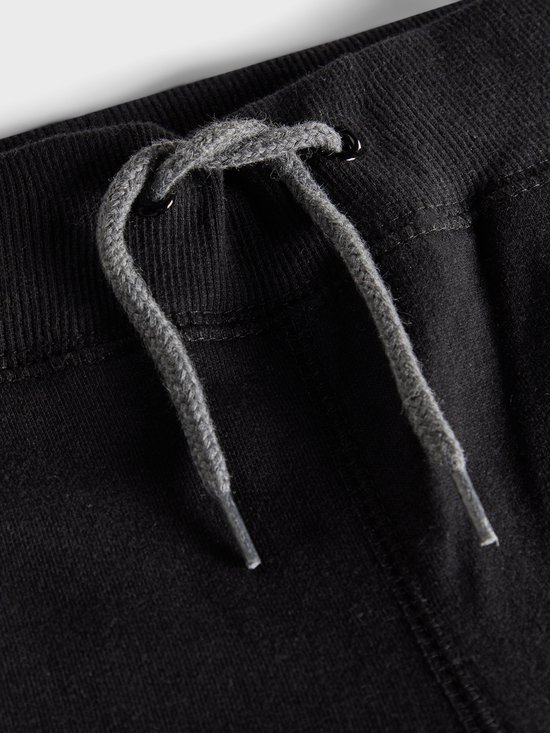 Detail van de tailleband van een zwarte joggingbroek met grijze veter