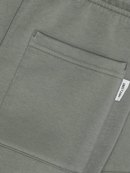 Close-up van de olijfgroene joggingbroek met een opgestikte zak en 'ONLY & SONS' label.