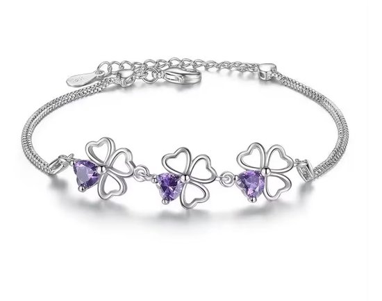 Bracelet en argent orné de trois breloques en forme de trèfle, chacune avec un cristal violet en forme de cœur. Les breloques sont reliées par une fine chaîne en argent.