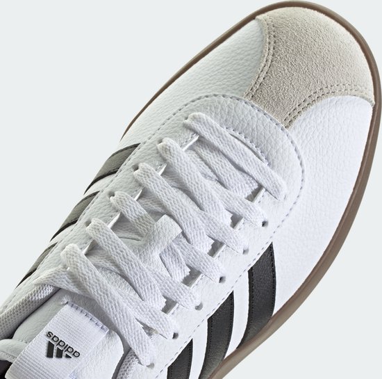 Detail van de witte adidas sneaker met veters, zwarte strepen en suède neus.