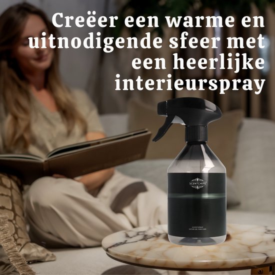 Zwarte interieurspray fles met spuitkop op een marmeren tafel, een vrouw leest een boek op de achtergrond.