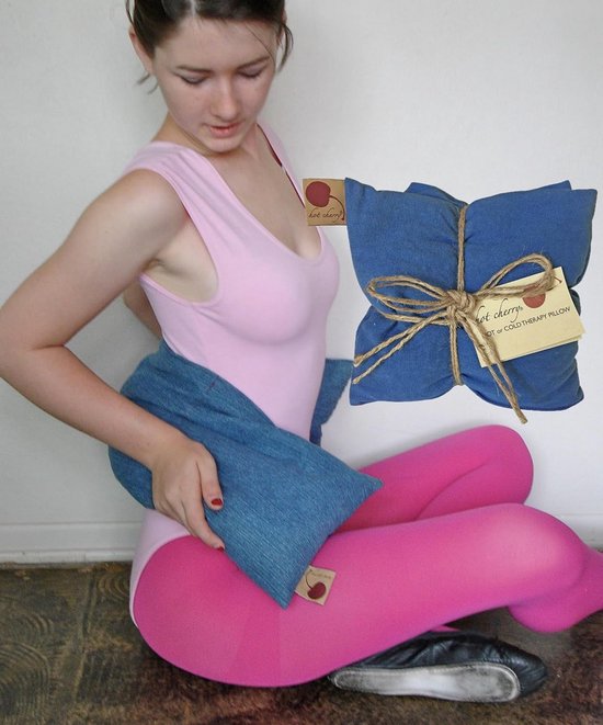 Jongedame in roze body en kniekousen met een blauw kersenpitkussen op haar heupen.