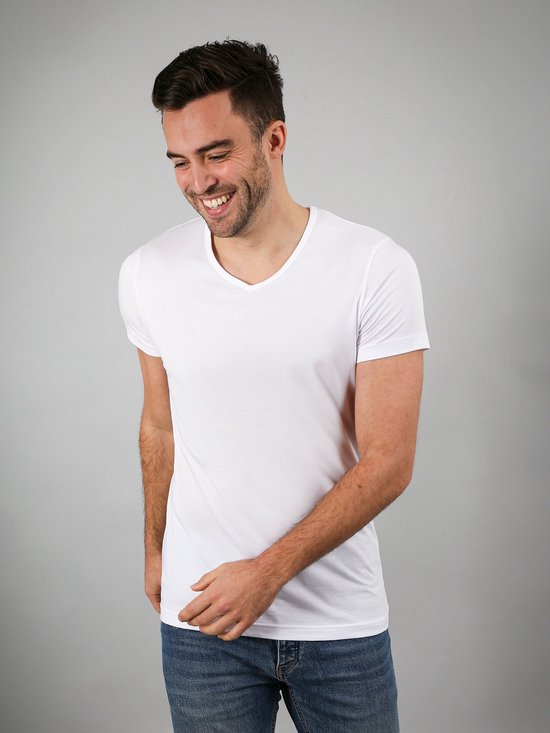 Lachende man in een wit V-hals T-shirt en spijkerbroek.