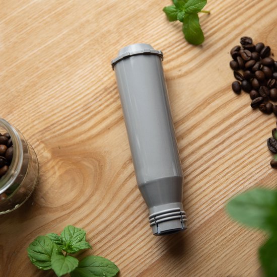 Grijs koffiefilter op een houten ondergrond met muntblaadjes en koffiebonen.