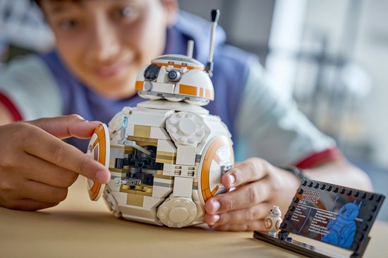 Un garçon montre un BB-8 LEGO avec un côté qui s'ouvre et un présentoir.