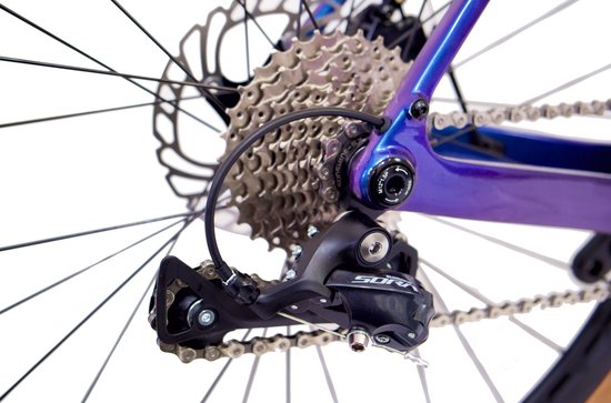 Close-up van de derailleur en cassette van een paarse Rinos gravelbike.
