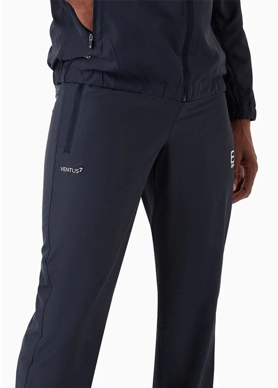 Detail van de linker broekspijp van een marineblauw EA7 trainingspak met 'VENTUS 7' logo en een ritszak.