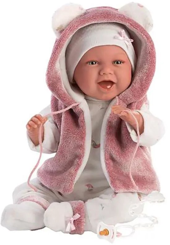 Zittende babypop Mimi in roze met witte berenjas, witte onesie met bloemetjes, en speen.
