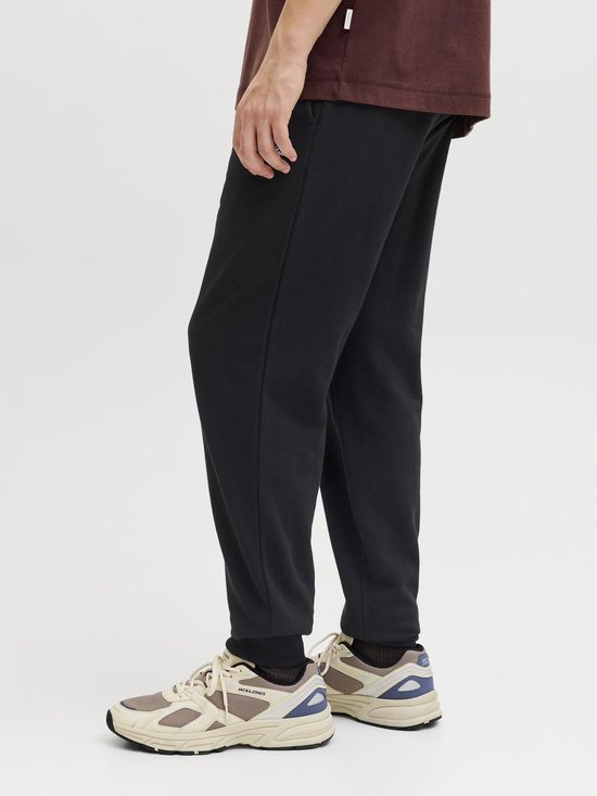 Close-up van een zwarte joggingbroek met op de linkerheup witte tekst.