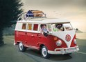 PLAYMOBIL Volkswagen T1 campingbus, rood en wit, met twee figuren op een landweg bij zonsondergang.