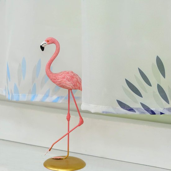 Een roze flamingo beeldje staat naast een transparant gordijn met een blauw bloemenpatroon.