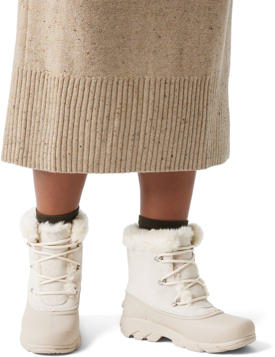 Een model draagt crème kleurige Sorel dames snowboots met witte bontrand.