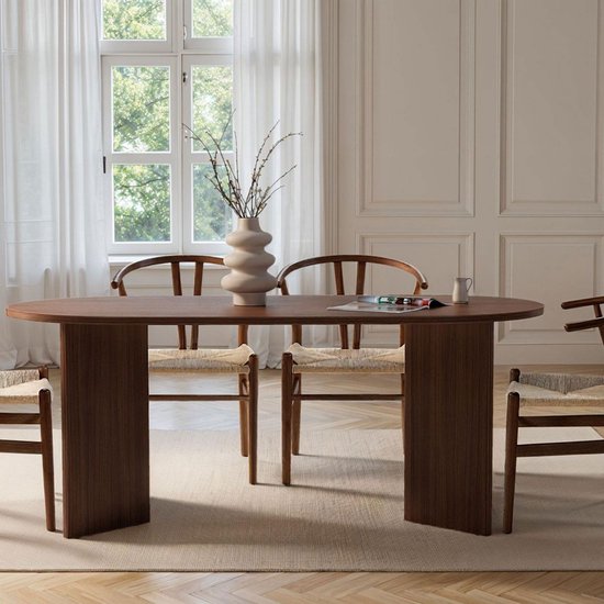 Ovale eettafel van donker hout met twee rechthoekige poten, omringd door stoelen met gebogen rugleuningen.