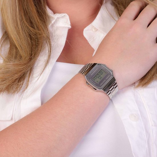 Zilverkleurig Casio horloge op de pols van een vrouw, gedragen met een wit shirt.