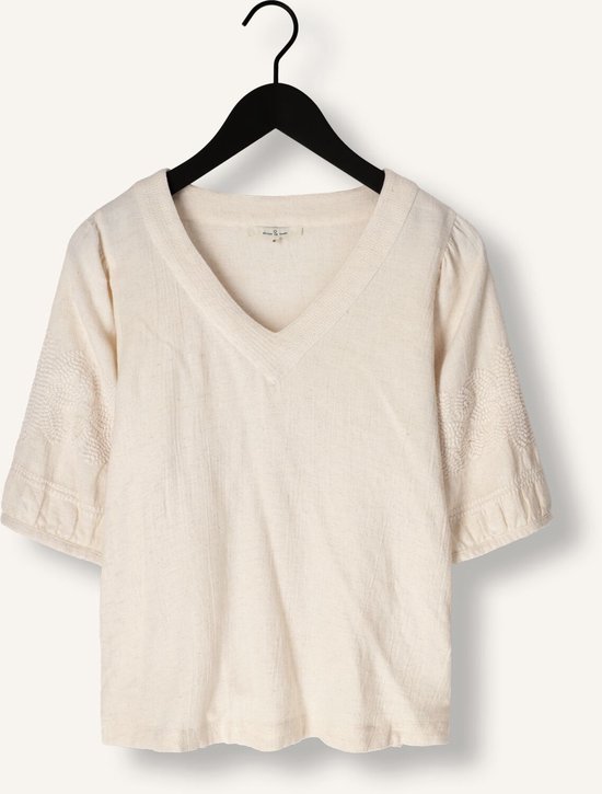 Ecru blouse met V-hals, kapmouwtjes en geborduurde details op de mouwen, hangend aan een kledinghanger.