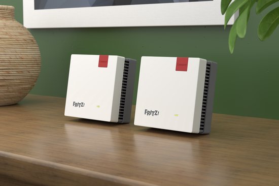 Twee witte Fritz! mesh-apparaten met rode accenten op een houten tafel.
