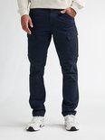 Donkerblauwe cargobroek met zakken, gedragen door een man met een beige sweater.