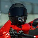 Insta360 actiecamera gemonteerd op de kin van een zwarte motorhelm op een rode motorfiets.