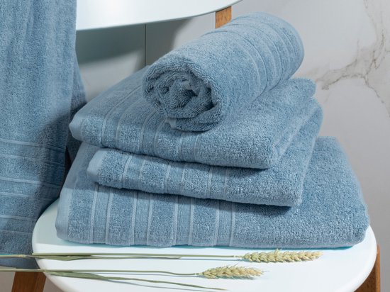 Pile de serviettes bleu clair et une serviette roulée sur une chaise blanche.