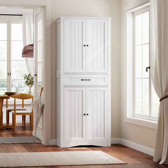 Armoire de cuisine blanche aux portes et tiroir fermés, dans un salon ou une salle à manger lumineuse, près d'une fenêtre et d'une table.