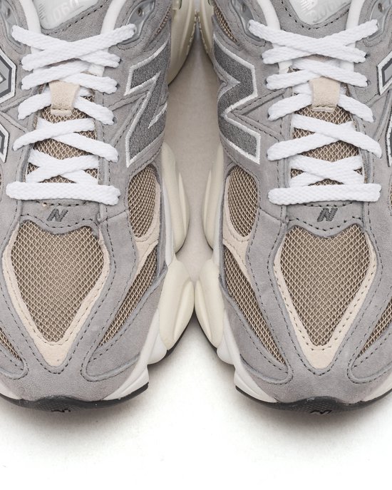 Detail van de voorkant van grijze New Balance U9060 sneakers met mesh en beige suède.