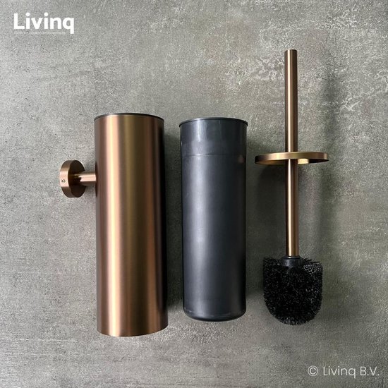Bronzen toiletborstel en binnenhouder naast elkaar op een grijze muur.