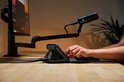 Zwarte Elgato XLR Dock MK.2 met microfoon op een arm en een persoon die een toetsenbord gebruikt.