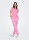 Model in roze Only Play T-shirt met korte mouwen en roze joggingbroek, met handen in de zakken.