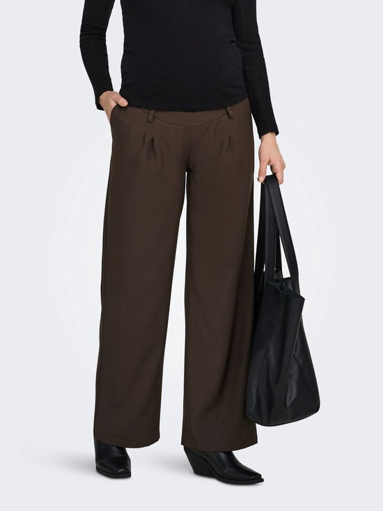 Zwangere vrouw in zwarte top en bruine wijde broek met plooien, draagt zwarte tas.