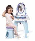 Een meisje met krullend haar zit op een blauw krukje en kamt haar haar bij een Frozen-kaptafel met spiegel.
