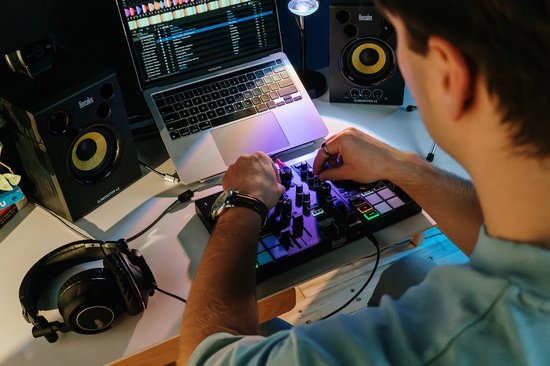 Man die DJ-controller bedient met een laptop, luidsprekers en koptelefoon.