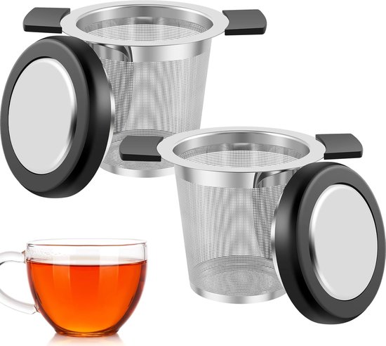 Twee roestvrijstalen theezeefjes met deksel en een glas warme thee.