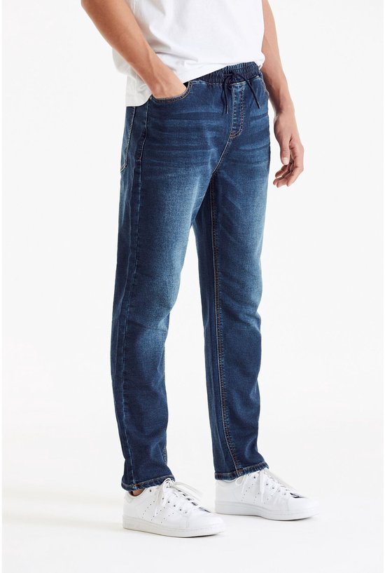Man draagt donkerblauwe jeans met elastische tailleband, trekkoord en steekzakken.