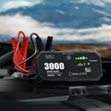 Zwarte jumpstarter met rode en zwarte klemmen geplaatst in een auto motorruimte.