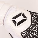 Detail van de witte band van de keepershandschoen met zwart logo. Zwarte en witte vingers met patroon.