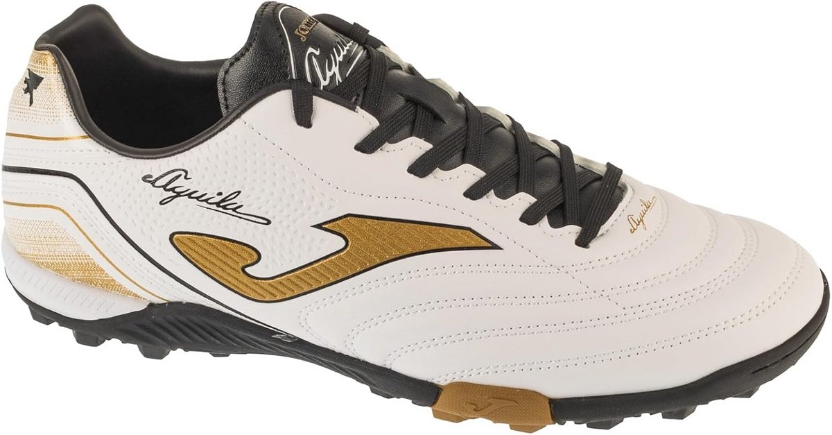 Witte turfvoetbaltrainers met zwarte en gouden accenten, ontworpen voor kunstgras en harde ondergronden.