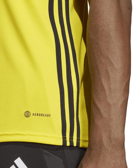 Close-up van de zijkant van een geel Adidas sportshirt met AERO READY-logo en zwarte strepen.