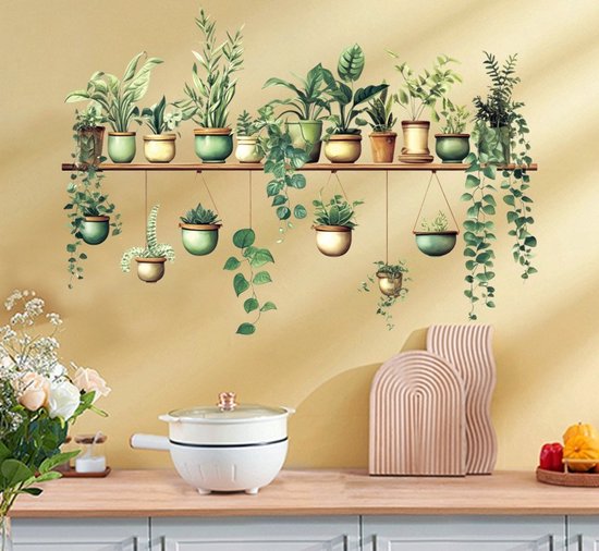 Une rangée de plantes vertes en pot, suspendues à une étagère en bois sur un mur jaune au-dessus d'un comptoir.