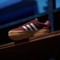 Bordeauxrode Adidas sneaker met witte strepen en dikke bruine zool.