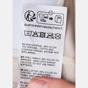 Waslabel met symbolen, tekst in het Zweeds, Engels en Duits, waaronder '85% NYLON 15% SPANDEX. WASH WITH SIMILAR COLOURS. DO NOT USE FABRIC SOFTENER.'