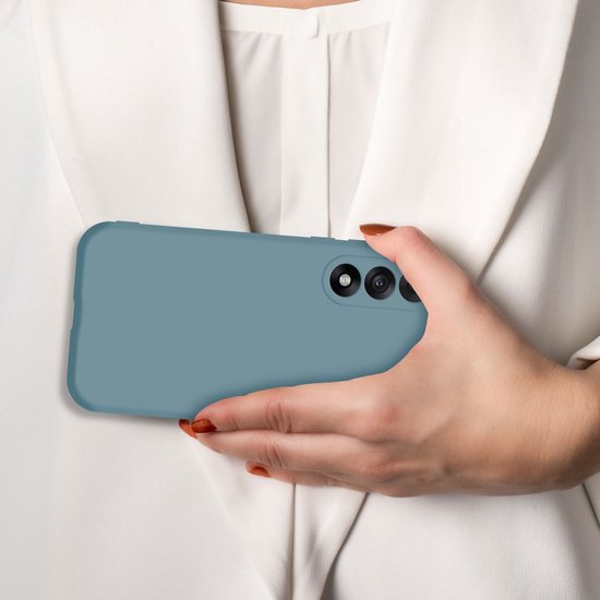 Een hand met oranje nagels houdt een matgroen telefoonhoesje horizontaal, met de achterkant naar voren. De mobiele telefoon is zichtbaar in het hoesje.