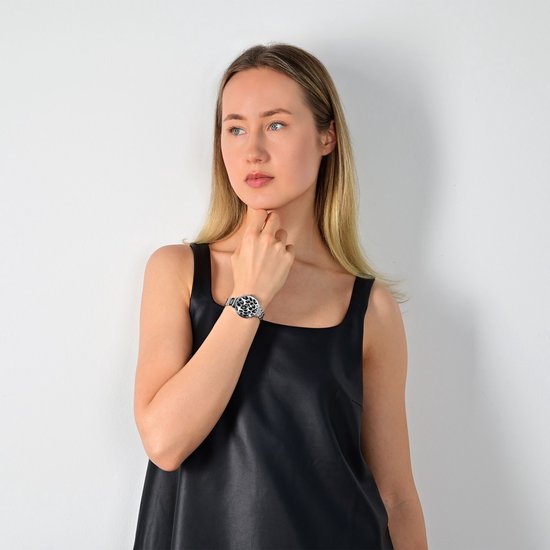 Vrouw met een zilverkleurig horloge met luipaardprint op haar linkerpols. Ze draagt een zwarte jurk.