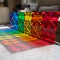 Een regenboog van transparante, veelkleurige magnetische tegels op een marmeren oppervlak.