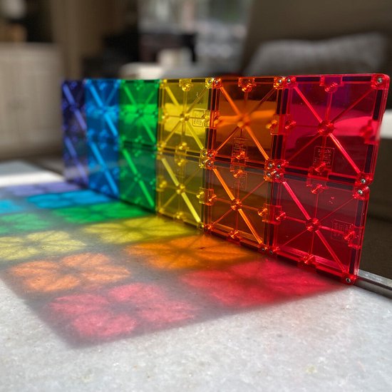 Een regenboog van transparante, veelkleurige magnetische tegels op een marmeren oppervlak.