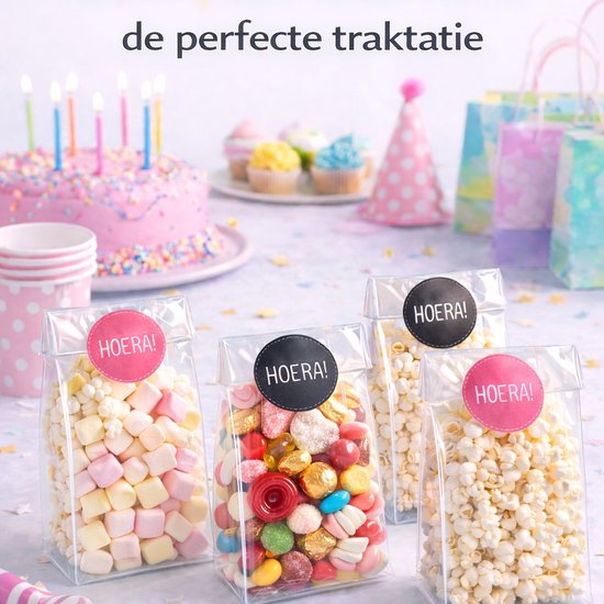 Vier transparante zakjes gevuld met popcorn en snoep, versierd met 'HOERA!' stickers.