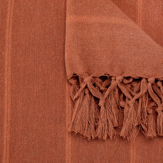 Gevouwen terracotta plaid met gedetailleerde franjes aan de rand.