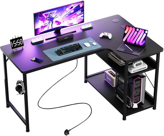 Zwart L-vormig bureau met koolstofvezelpatroon, voorzien van monitor, laptop, toetsenbord, controller en headset.